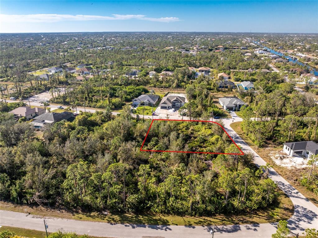 An aerial view shows a vacant, wooded residential lot outlined in red between two roads — 8281 CONSUL STREET, PORT CHARLOTTE, FL