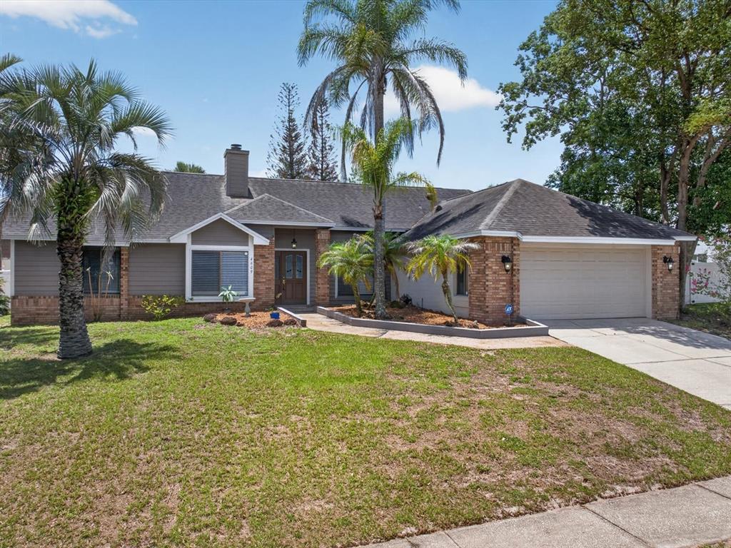 A single-story house with a brick and siding facade, a two-car garage, and palm trees — 4609 TIFFANY WOODS CIRCLE, OVIEDO, FL