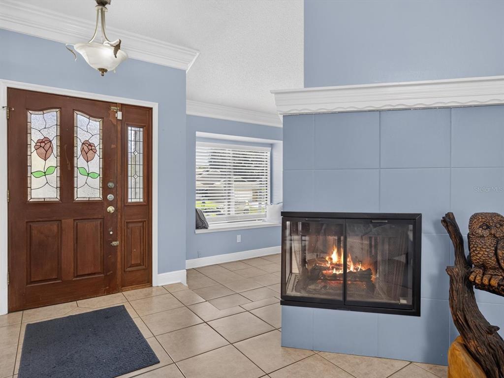 An entryway features a wood front door with stained glass, tile flooring, and a fireplace — 4609 TIFFANY WOODS CIRCLE, OVIEDO, FL