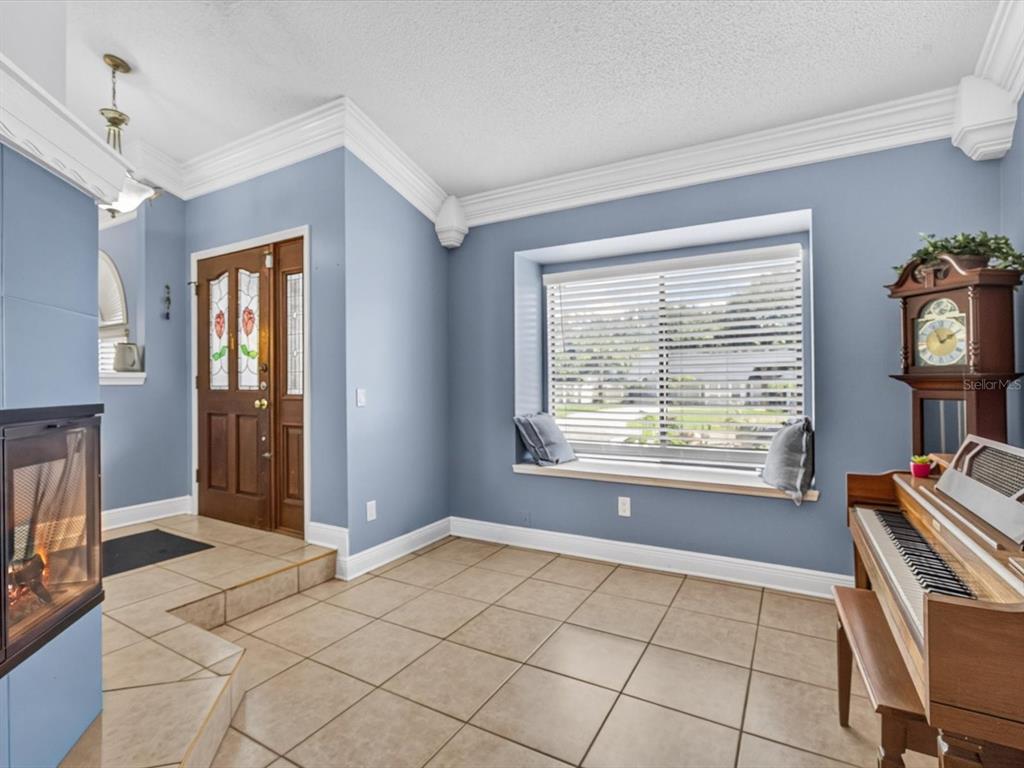 A room with blue walls, tile flooring, a bay window, a fireplace, and a piano — 4609 TIFFANY WOODS CIRCLE, OVIEDO, FL