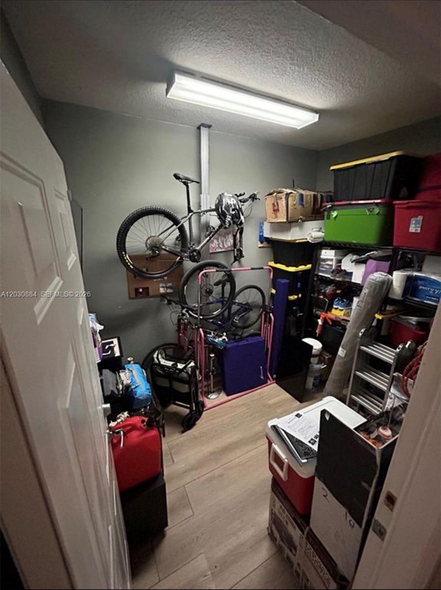 A small storage room features wood-look flooring, a ceiling light, and wall-mounted bicycle storage — 15372 SW 9th Way, Miami FL 33194, MIAMI, FL