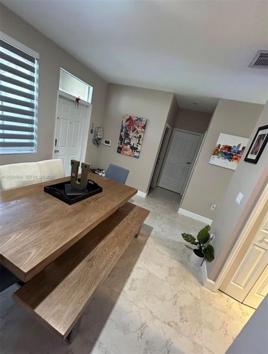 A dining area features a wooden table with a bench, tile flooring, and wall art — 15372 SW 9th Way, Miami FL 33194, MIAMI, FL