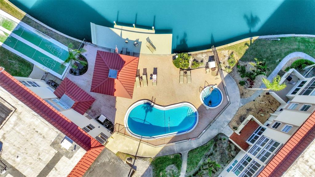 An aerial view of a swimming pool, hot tub, and shuffleboard court near a canal — 113 ISLAND WAY UNIT 241, CLEARWATER BEACH, FL