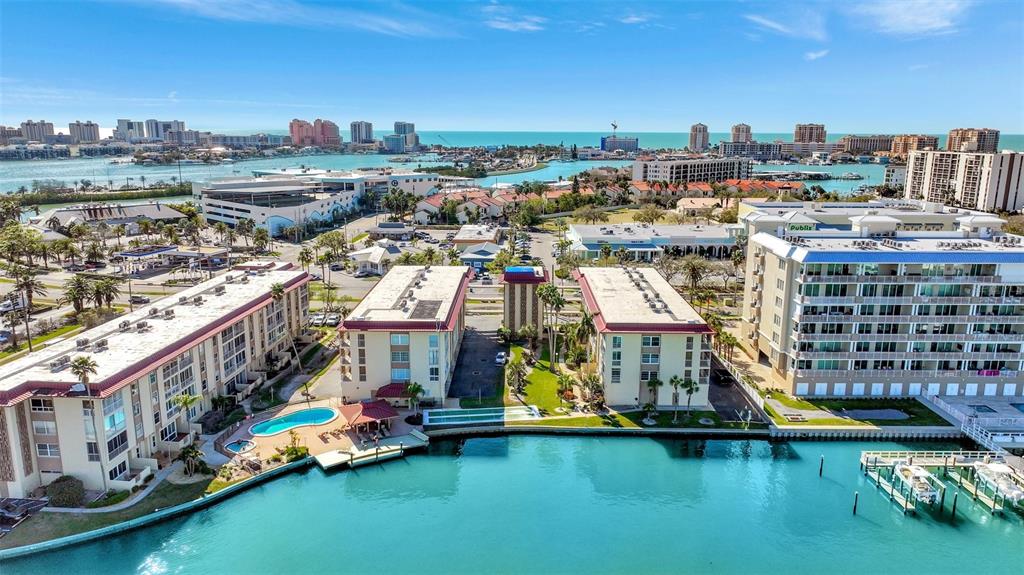 An aerial view shows waterfront apartment buildings with swimming pools and boat docks — 113 ISLAND WAY UNIT 241, CLEARWATER BEACH, FL