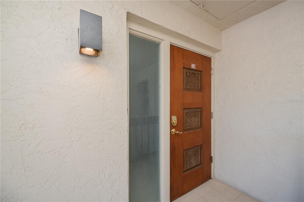A wooden front door with a side window and a wall-mounted light fixture — 4396 BOWSPRIT COURT UNIT 4E, FORT MYERS, FL