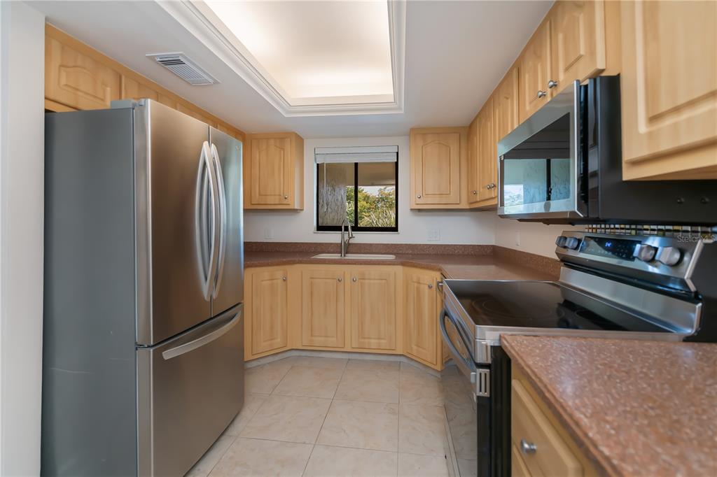 A kitchen features light wood cabinets, stainless steel appliances, and brown countertops — 4396 BOWSPRIT COURT UNIT 4E, FORT MYERS, FL