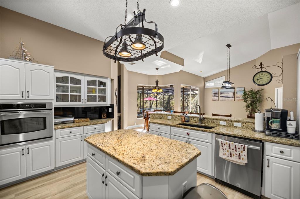 A kitchen featuring white cabinets, granite countertops, a center island, and stainless steel appliances — 4860 W ANGUS DRIVE, BEVERLY HILLS, FL