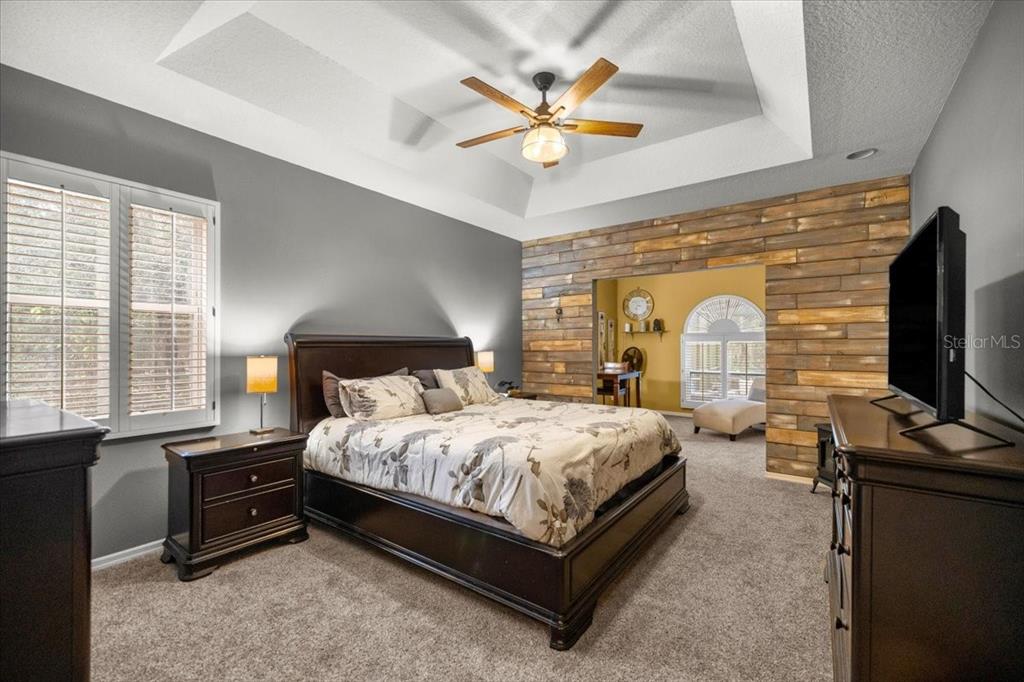 A bedroom features a tray ceiling, a wood-plank accent wall, and an attached sitting area — 4860 W ANGUS DRIVE, BEVERLY HILLS, FL