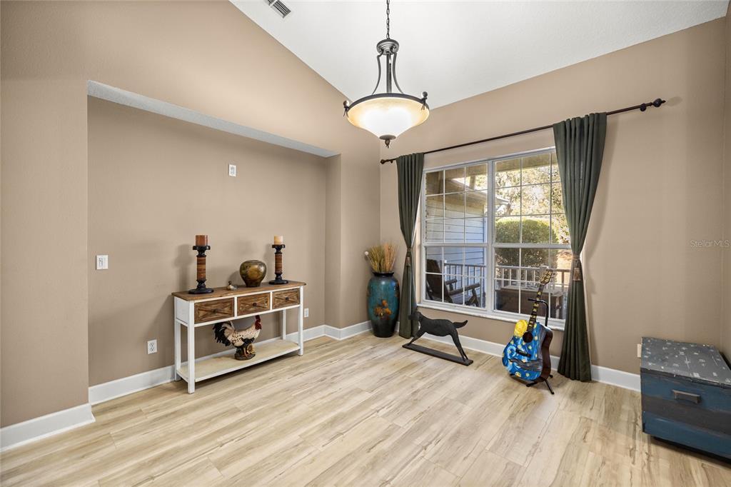 A dining room with light wood flooring, a white console table, and a large window — 4860 W ANGUS DRIVE, BEVERLY HILLS, FL