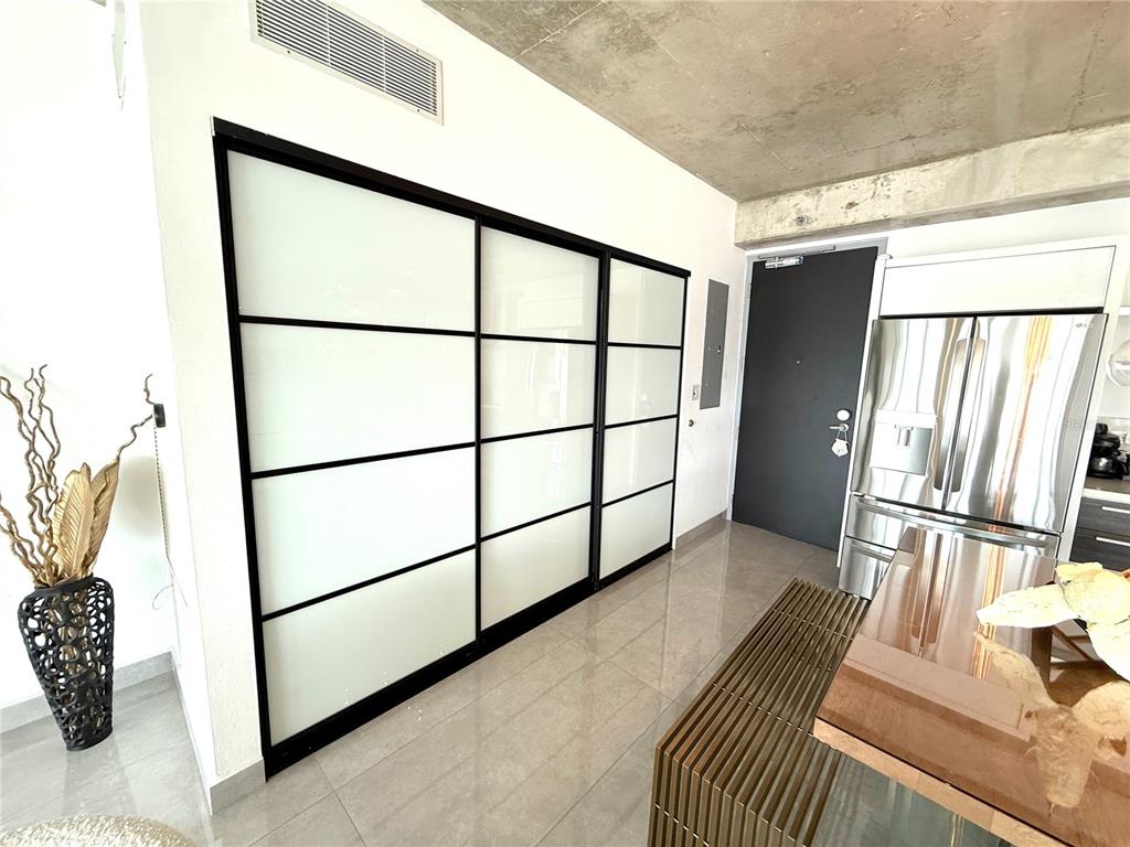 A modern kitchen features a concrete ceiling, glossy white cabinets, and a glass-based dining table — 403 DE LA CONSTITUCIÓN AVENUE UNIT 906, SAN JUAN, PR