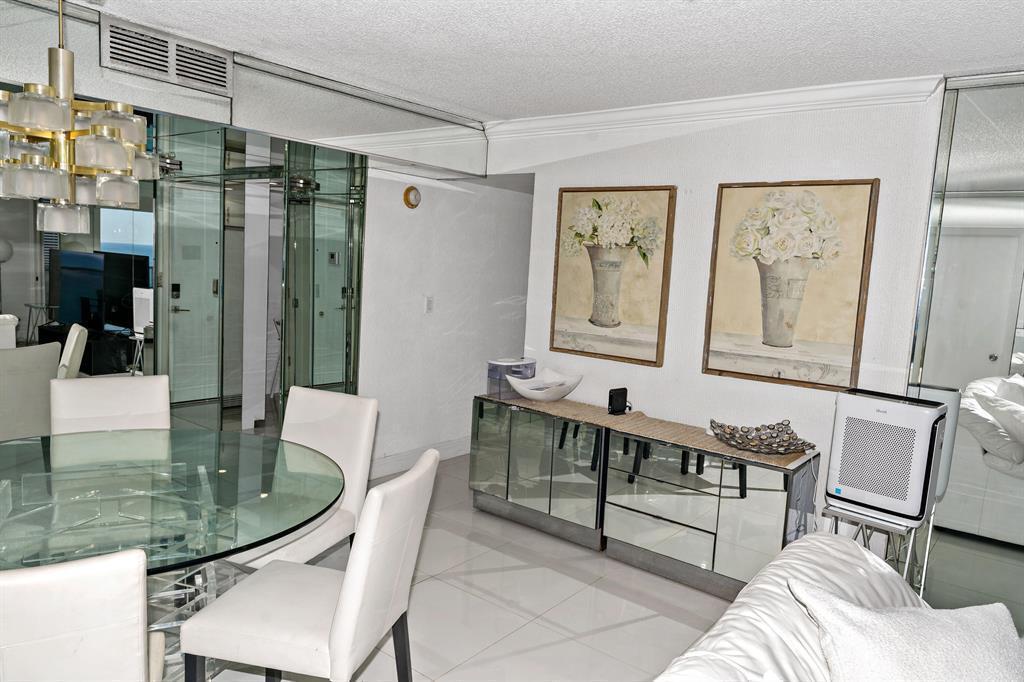 A dining area features a glass table, mirrored sideboard, and two floral wall art pieces — 1880 S Ocean Drive, Hallandale Beach FL 33009, HALLANDALE BEACH, FL