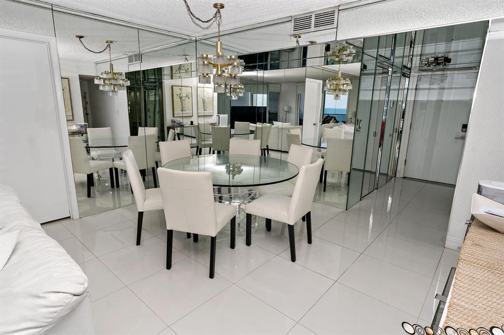 A dining room with a glass table, white chairs, and mirrored walls on white tile floors — 1880 S Ocean Drive, Hallandale Beach FL 33009, HALLANDALE BEACH, FL