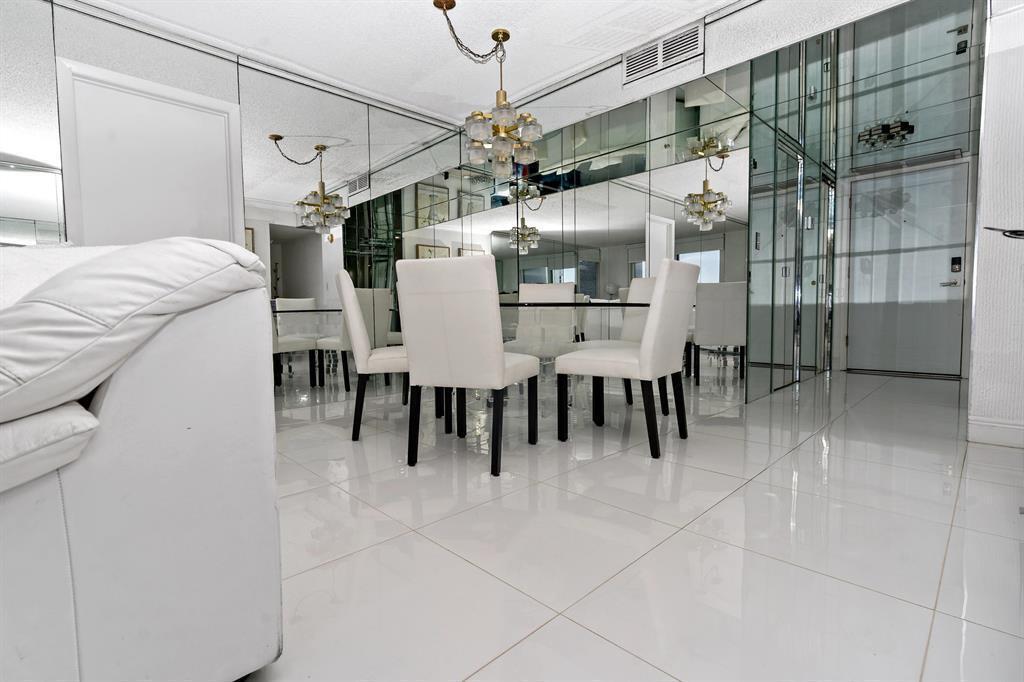 A dining area features a glass table, white chairs, tiled floors, and mirrored walls — 1880 S Ocean Drive, Hallandale Beach FL 33009, HALLANDALE BEACH, FL
