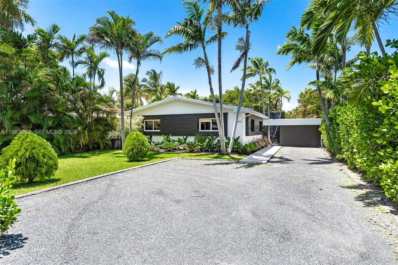A wooden deck with outdoor furniture overlooks a canal with a boat and lush greenery — 1865 Daytonia Rd, Miami Beach FL 33141, MIAMI BEACH, FL