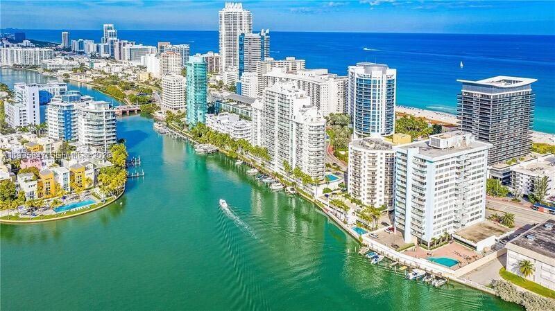 An aerial view shows high-rise buildings along a canal leading to the ocean — 5880 Collins Ave # 302, Miami Beach FL 33140, MIAMI BEACH, FL