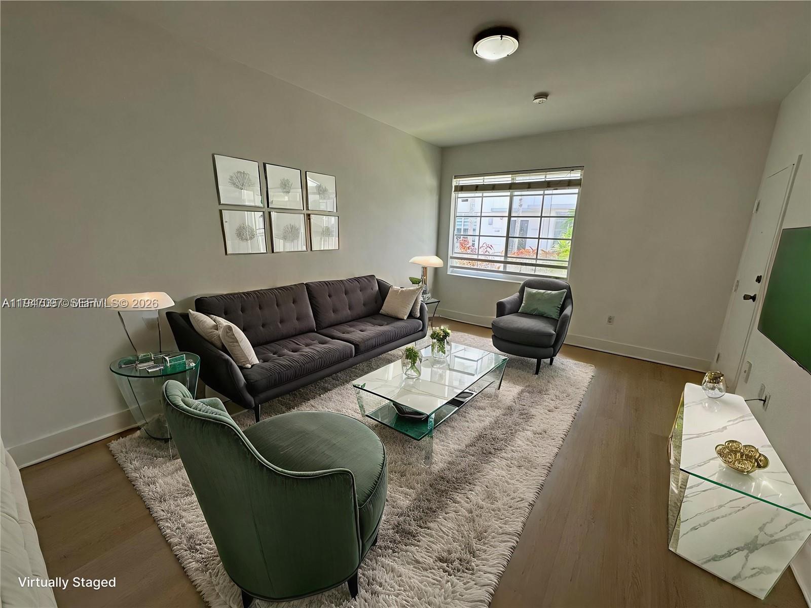 This virtually staged living room features a dark sofa, glass coffee table, and area rug — 1000 Meridian Ave # 17, Miami Beach FL 33139, MIAMI BEACH, FL