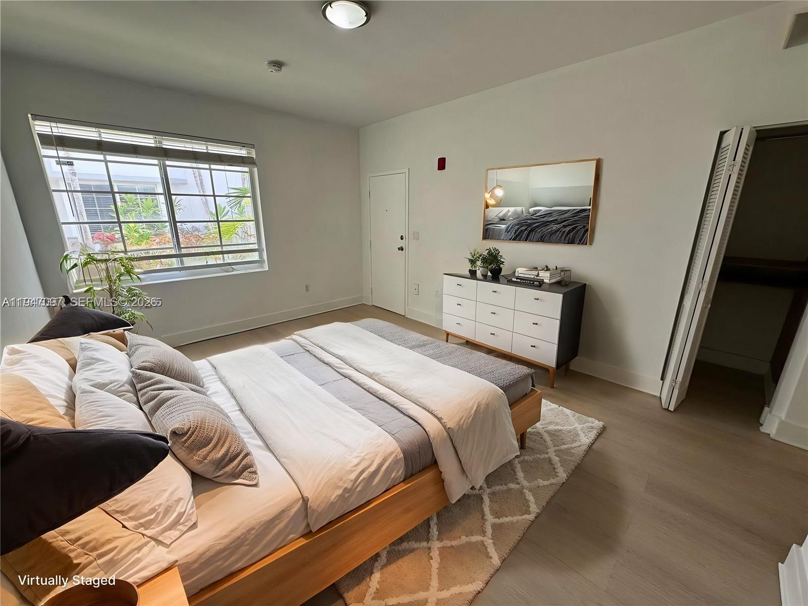 A bedroom features a wooden bed frame, a white dresser with a mirror, and light flooring — 1000 Meridian Ave # 17, Miami Beach FL 33139, MIAMI BEACH, FL