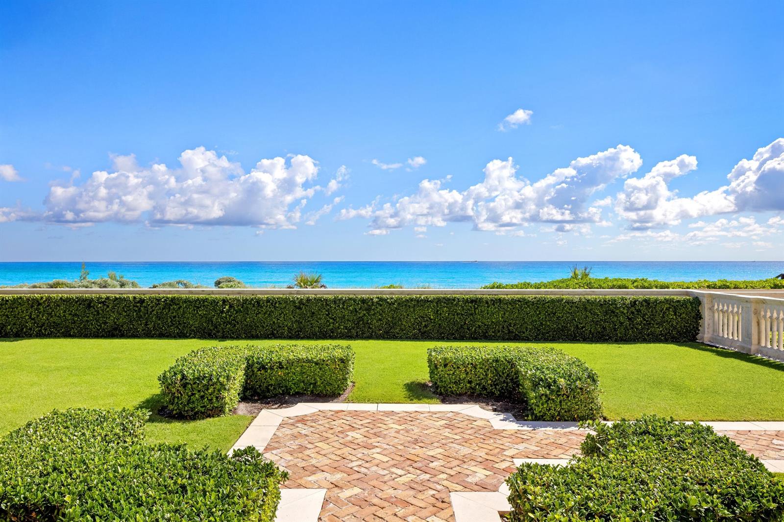 A manicured lawn and brick patio overlook a hedge-lined terrace with an ocean view — 1620 S Ocean Boulevard, Palm Beach FL 33480, PALM BEACH, FL