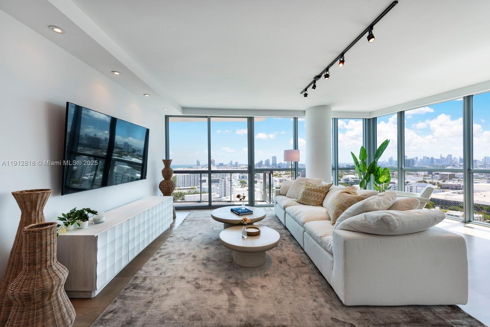 A modern living room features a white sofa, two round coffee tables, and floor-to-ceiling windows — 101 20th St # 3006, Miami Beach FL 33139, MIAMI BEACH, FL