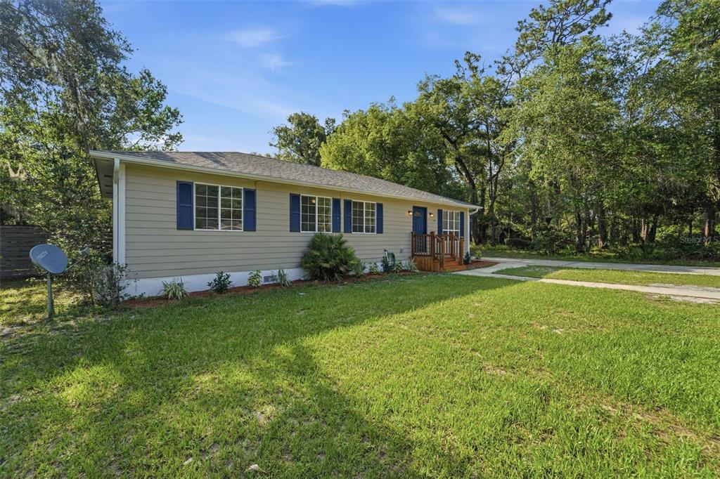 A single-story house with tan siding, blue shutters, and a small wooden front porch — 451 S BLUE LAKE AVENUE, DELAND, FL