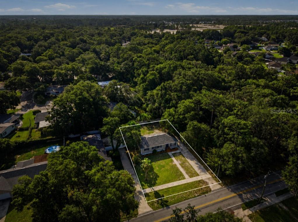 An aerial view shows a single-story house with a large yard surrounded by dense trees — 451 S BLUE LAKE AVENUE, DELAND, FL