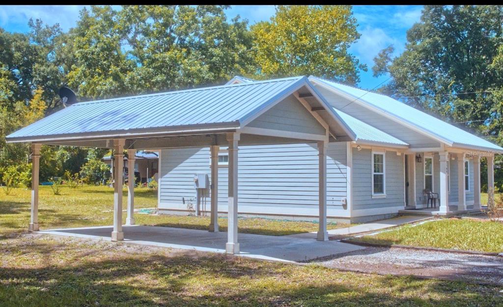 A light blue house with a metal roof and a large attached front carport — 3109 E BRYANT AVENUE, BELL, FL