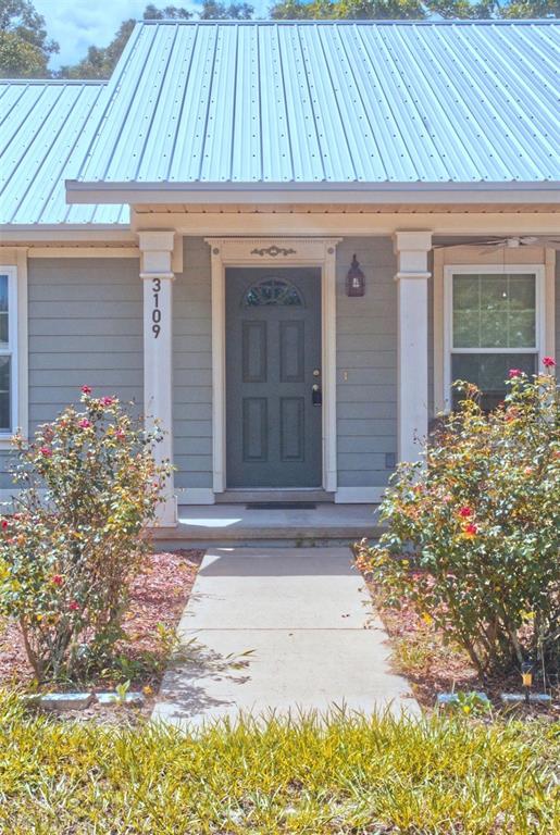 The exterior of a house features a metal roof, a dark door, and a walkway — 3109 E BRYANT AVENUE, BELL, FL