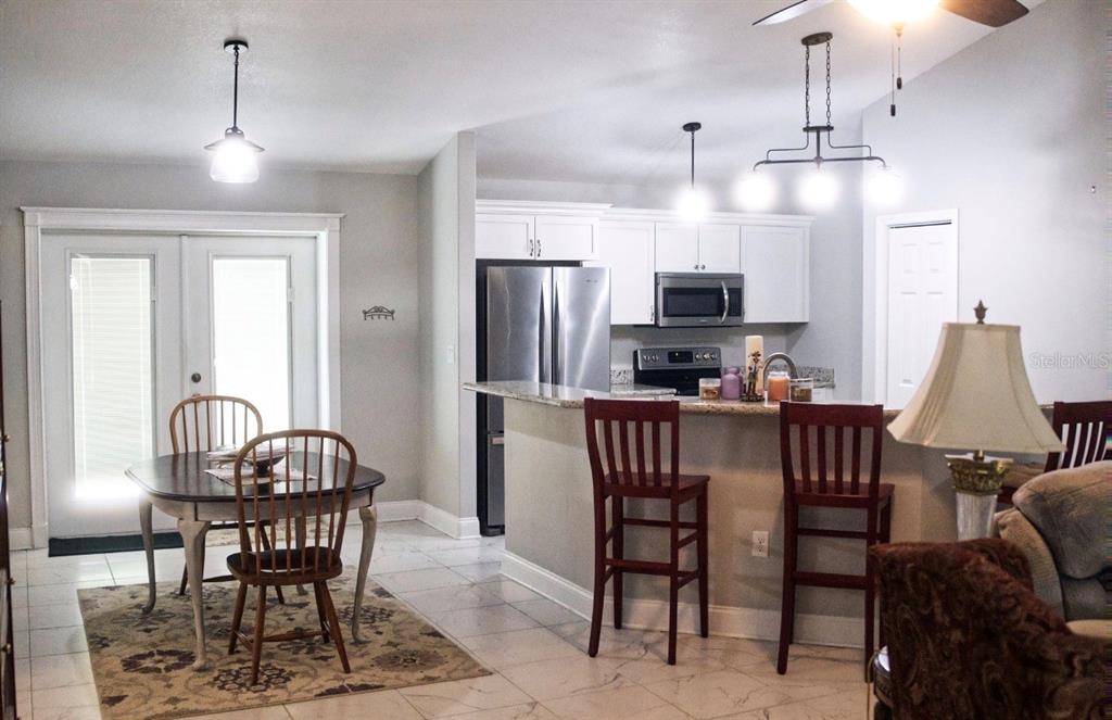 A kitchen with white cabinets and stainless steel appliances opens to a dining area — 3109 E BRYANT AVENUE, BELL, FL