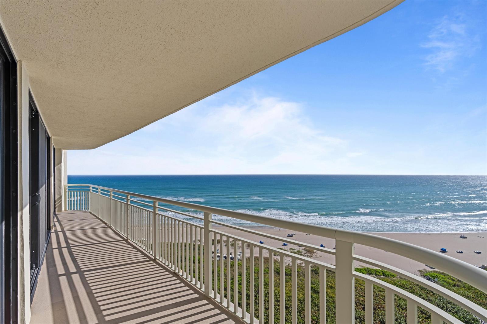 A balcony with a white railing overlooks a sandy beach and the ocean — 3000 N Ocean Drive # C, Singer Island FL 33404, SINGER ISLAND, FL