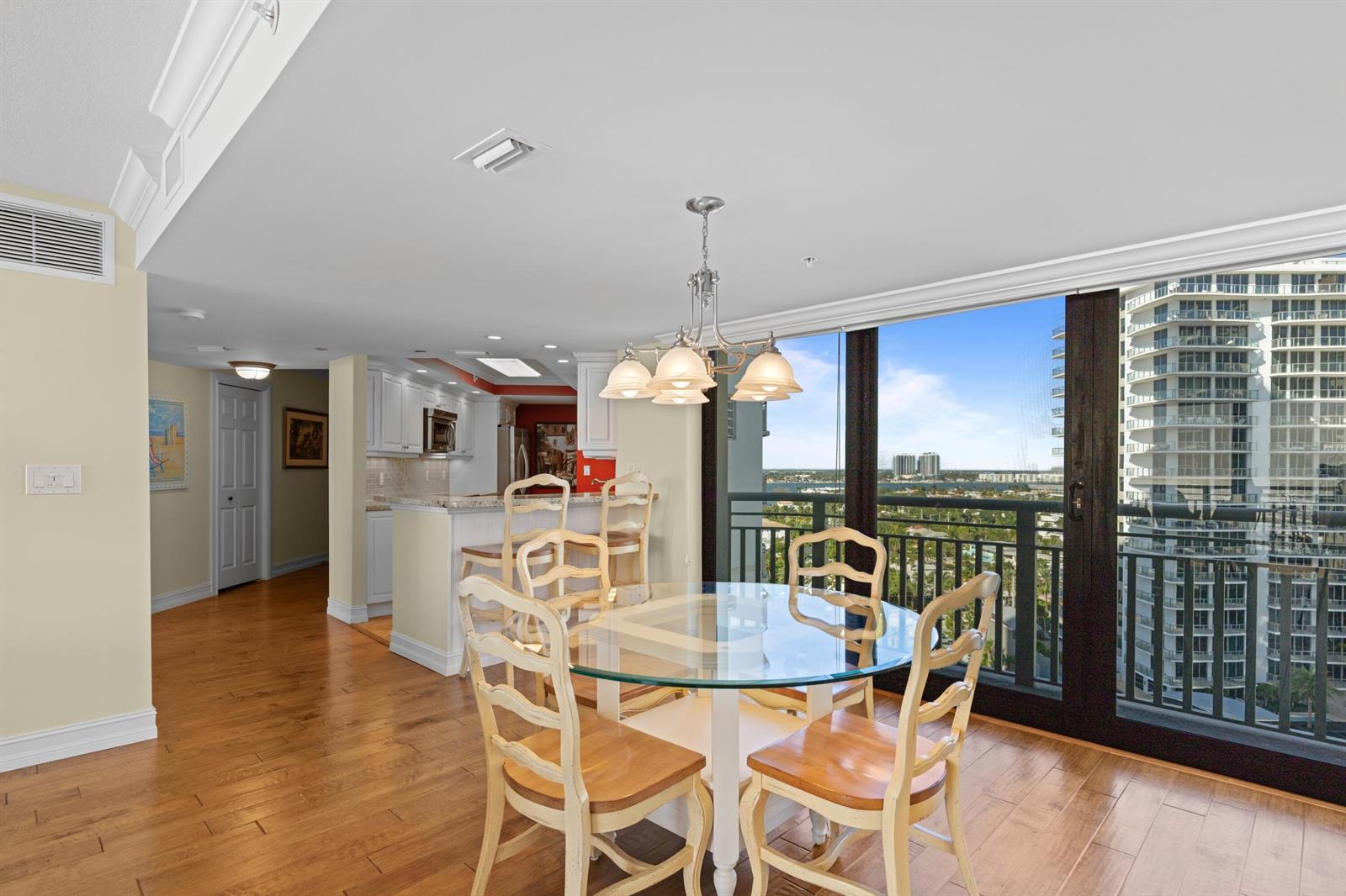 A dining area with a glass table and chairs overlooks a balcony and city skyline — 3000 N Ocean Drive # C, Singer Island FL 33404, SINGER ISLAND, FL