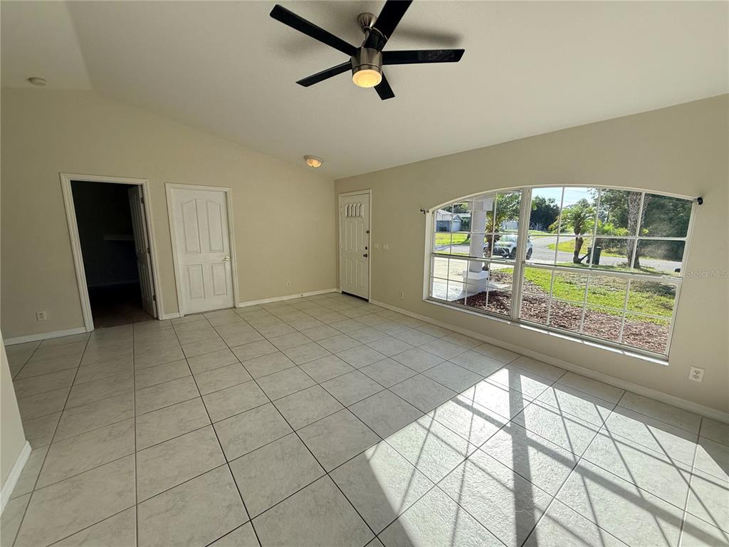 An empty room features light-colored tile flooring, a ceiling fan, and a large arched window — 4185 AMARI ROAD, NORTH PORT, FL