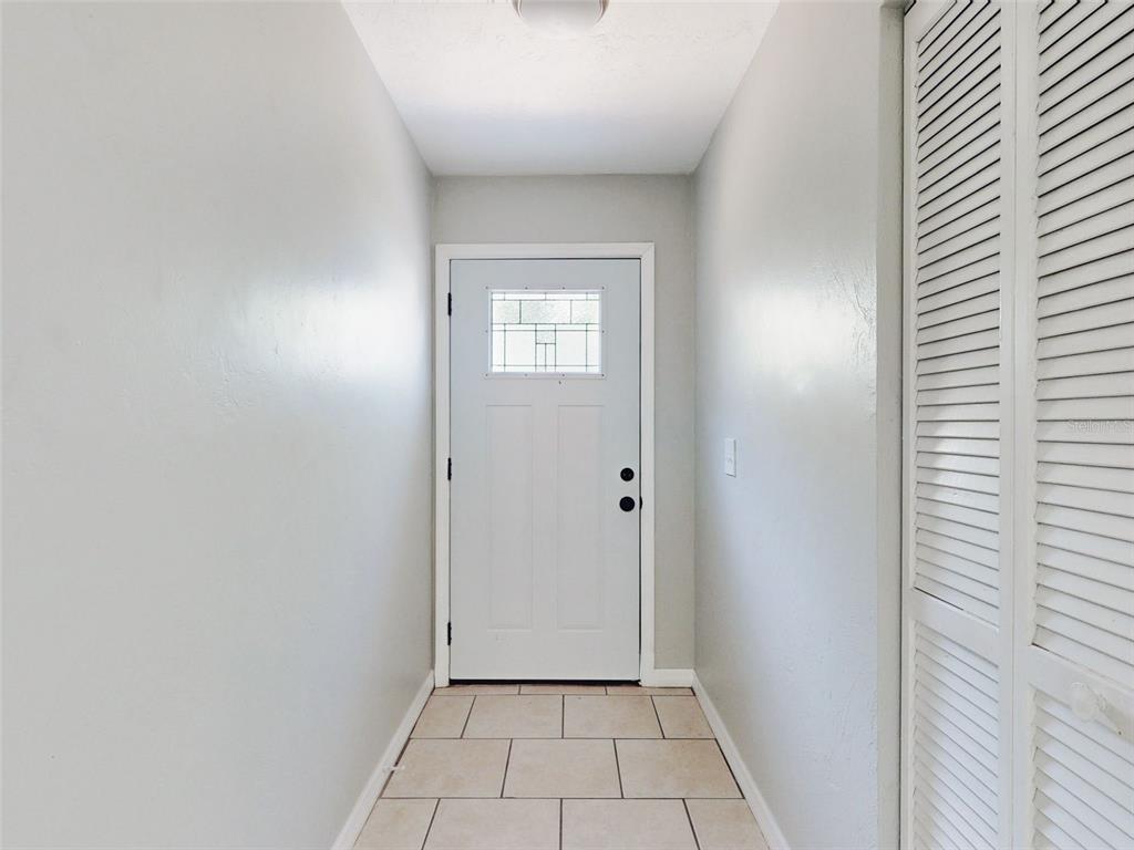 A white front door with a glass window sits at the end of a tiled entryway — 1307 BOND STREET, EDGEWATER, FL