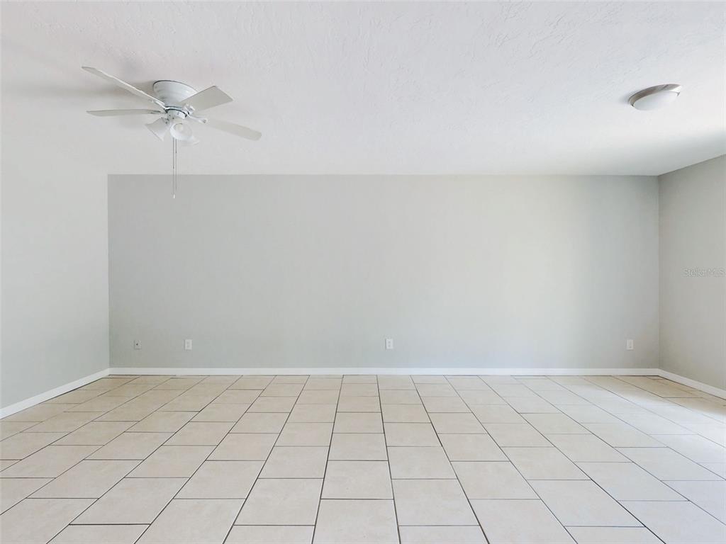 An empty room with light-colored tile flooring, a ceiling fan, and plain gray walls — 1307 BOND STREET, EDGEWATER, FL