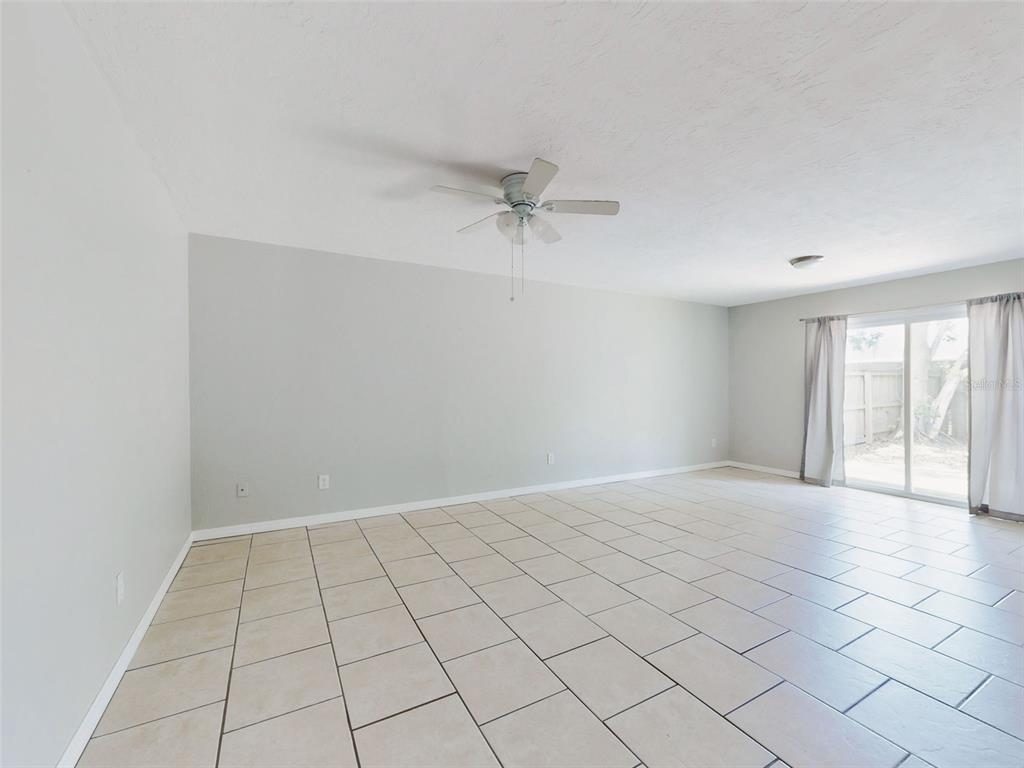A spacious, empty room features light gray walls, large beige floor tiles, and a ceiling fan — 1307 BOND STREET, EDGEWATER, FL