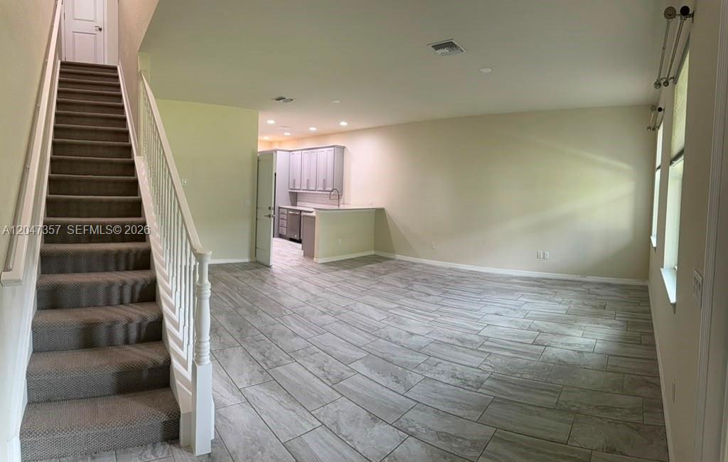 An open-concept living area features gray tile flooring, a carpeted staircase, and a kitchen background — 4022 Long Leaf Ln # 4022, Hollywood FL 33021, HOLLYWOOD, FL