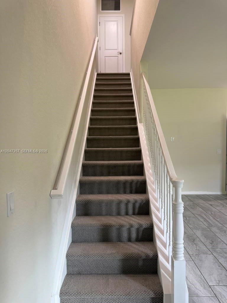 A straight staircase with gray carpet and white railings leads to a closed door — 4022 Long Leaf Ln # 4022, Hollywood FL 33021, HOLLYWOOD, FL