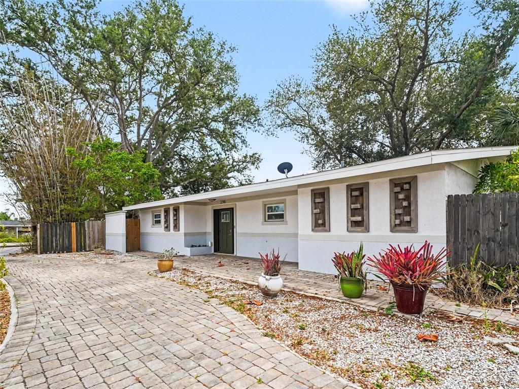 A single-story house with a paved driveway, white stucco walls, and decorative wooden window frames — 2746 HIBISCUS STREET, SARASOTA, FL