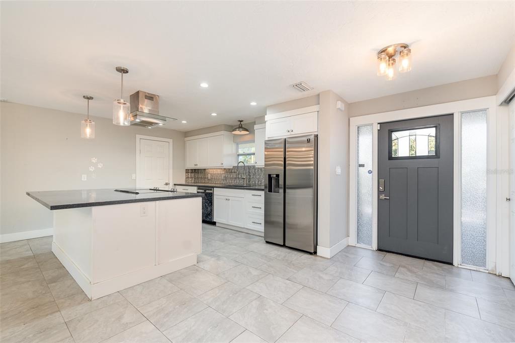 A kitchen features a central island, stainless steel refrigerator, white cabinetry, and gray tile flooring — 2746 HIBISCUS STREET, SARASOTA, FL