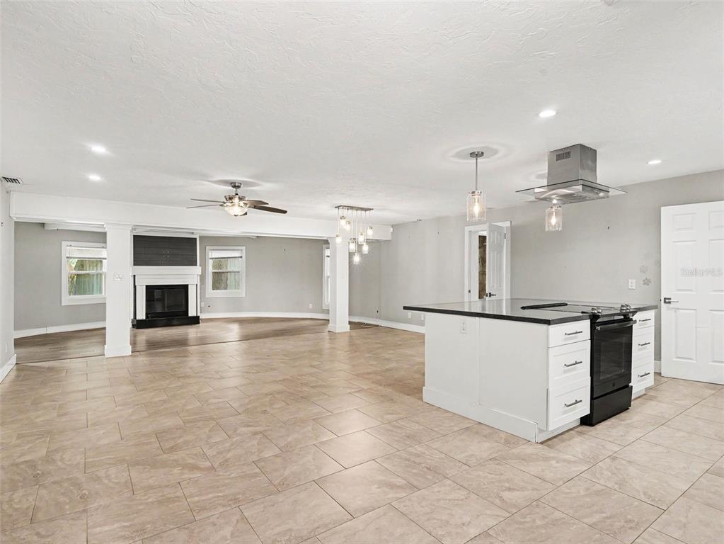 An open-concept kitchen and living area features tile flooring, a kitchen island, and a fireplace — 2746 HIBISCUS STREET, SARASOTA, FL