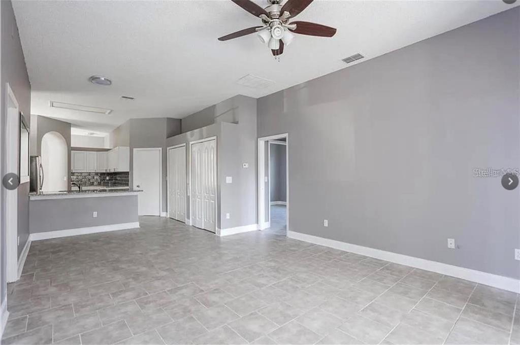 An open-concept living area features gray walls, tile flooring, and a ceiling fan — 12834 WOODBURY GLEN DRIVE, ORLANDO, FL