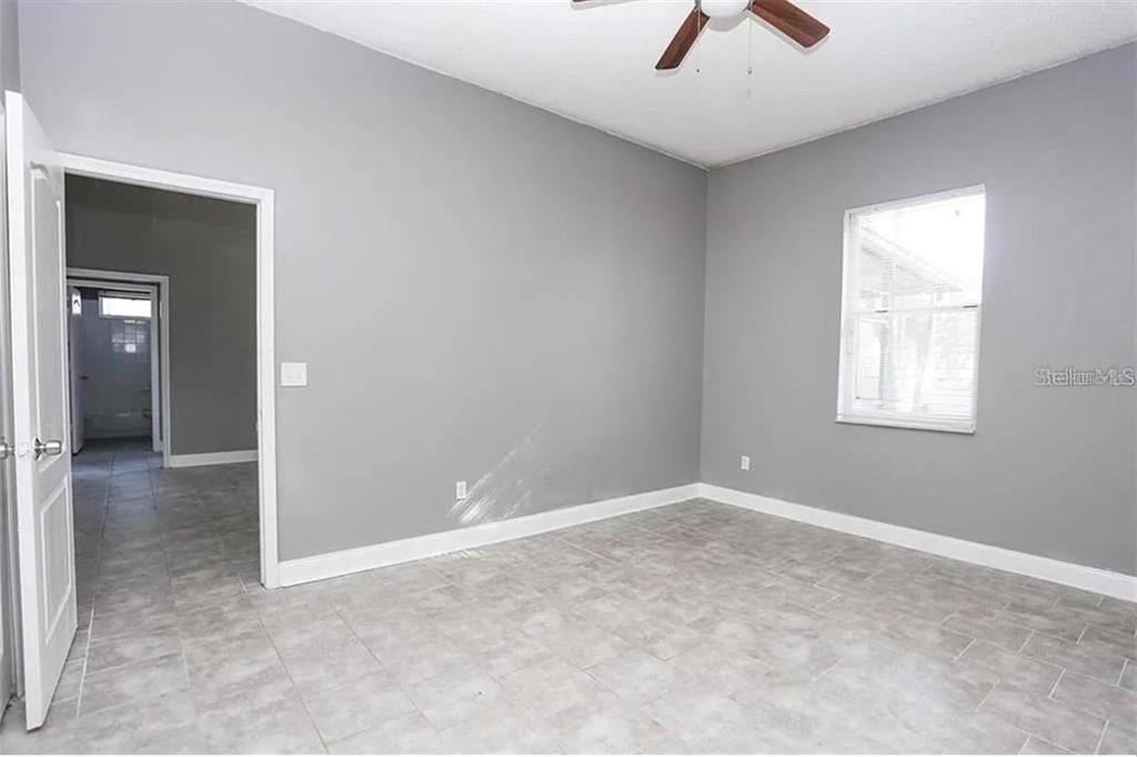 An empty bedroom features gray walls, white trim, tile flooring, and a ceiling fan — 12834 WOODBURY GLEN DRIVE, ORLANDO, FL