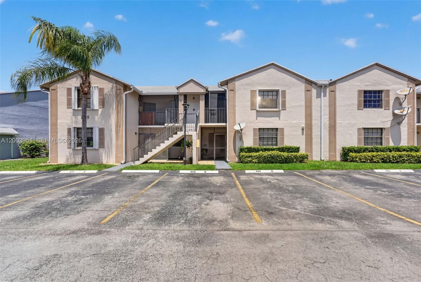 A two-story apartment building features beige stucco walls, brown shutters, and an exterior staircase — 889 Hamilton Dr # 889D, Homestead FL 33034, HOMESTEAD, FL