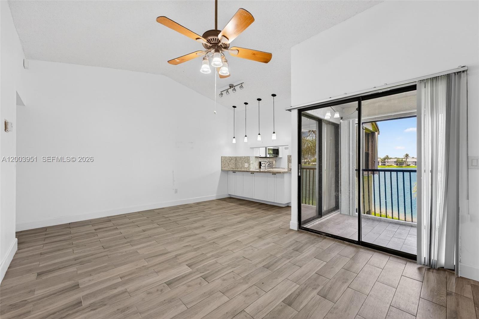 An open-concept living area features wood-look tile floors, a ceiling fan, and a sliding glass door — 889 Hamilton Dr # 889D, Homestead FL 33034, HOMESTEAD, FL