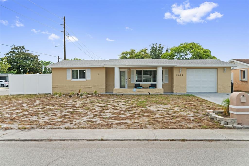 A single-story house with a tan exterior, white garage door, and a front porch — 3619 QUINTEN DRIVE, NEW PORT RICHEY, FL