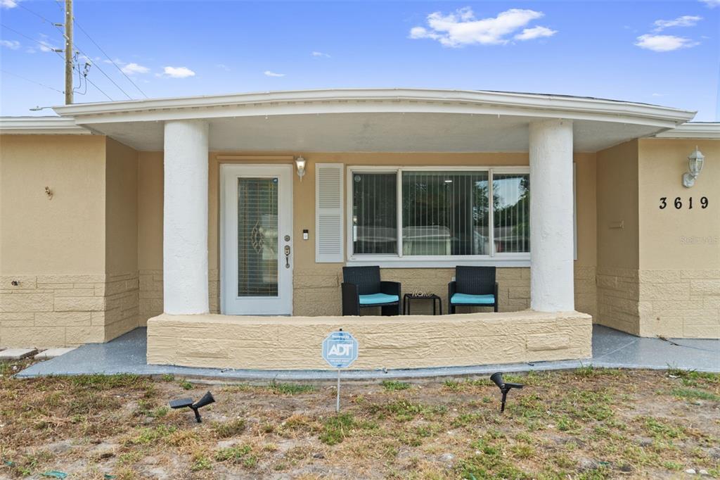 The exterior of a house features a covered porch with two columns and a front door — 3619 QUINTEN DRIVE, NEW PORT RICHEY, FL
