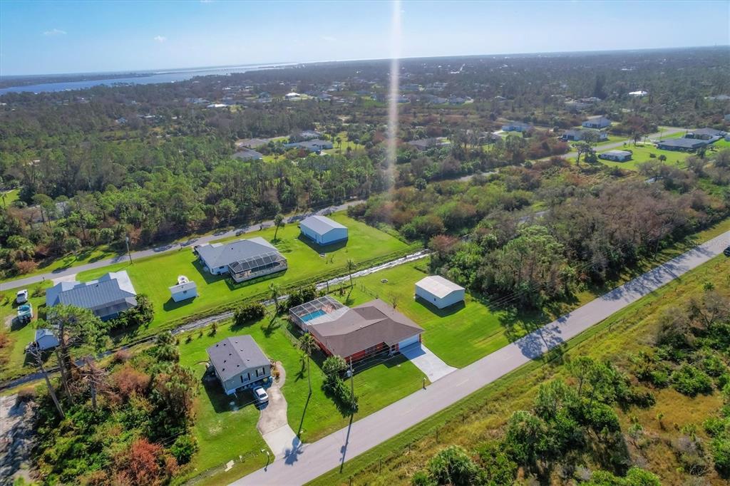 An aerial view shows several houses with pools and outbuildings surrounded by trees and roads — 4154 JENNINGS BOULEVARD PORT, PORT CHARLOTTE, FL