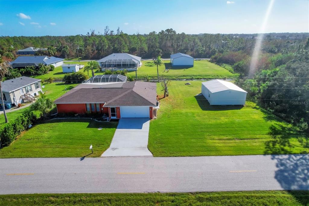 An aerial view shows a single-story house with a garage and a detached metal building — 4154 JENNINGS BOULEVARD PORT, PORT CHARLOTTE, FL