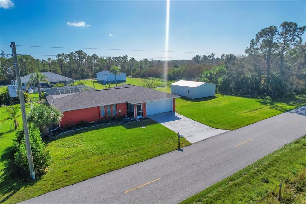 An aerial view shows a red house with a garage, a shed, and a paved driveway — 4154 JENNINGS BOULEVARD PORT, PORT CHARLOTTE, FL