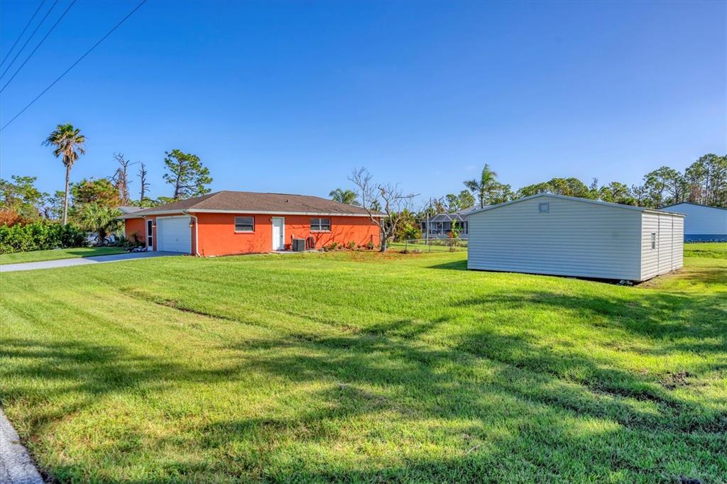 An orange house with a white garage and a separate detached shed on a lawn — 4154 JENNINGS BOULEVARD PORT, PORT CHARLOTTE, FL