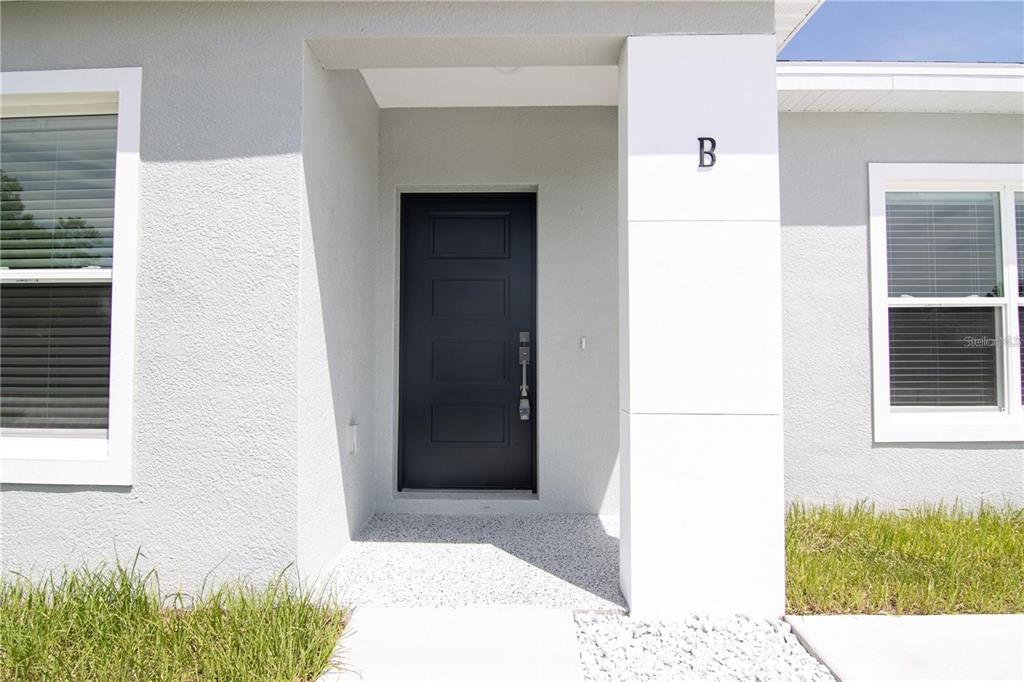 A modern home exterior features a dark front door and a white pillar labeled B — 2232 FERNWOOD STREET, DELTONA, FL